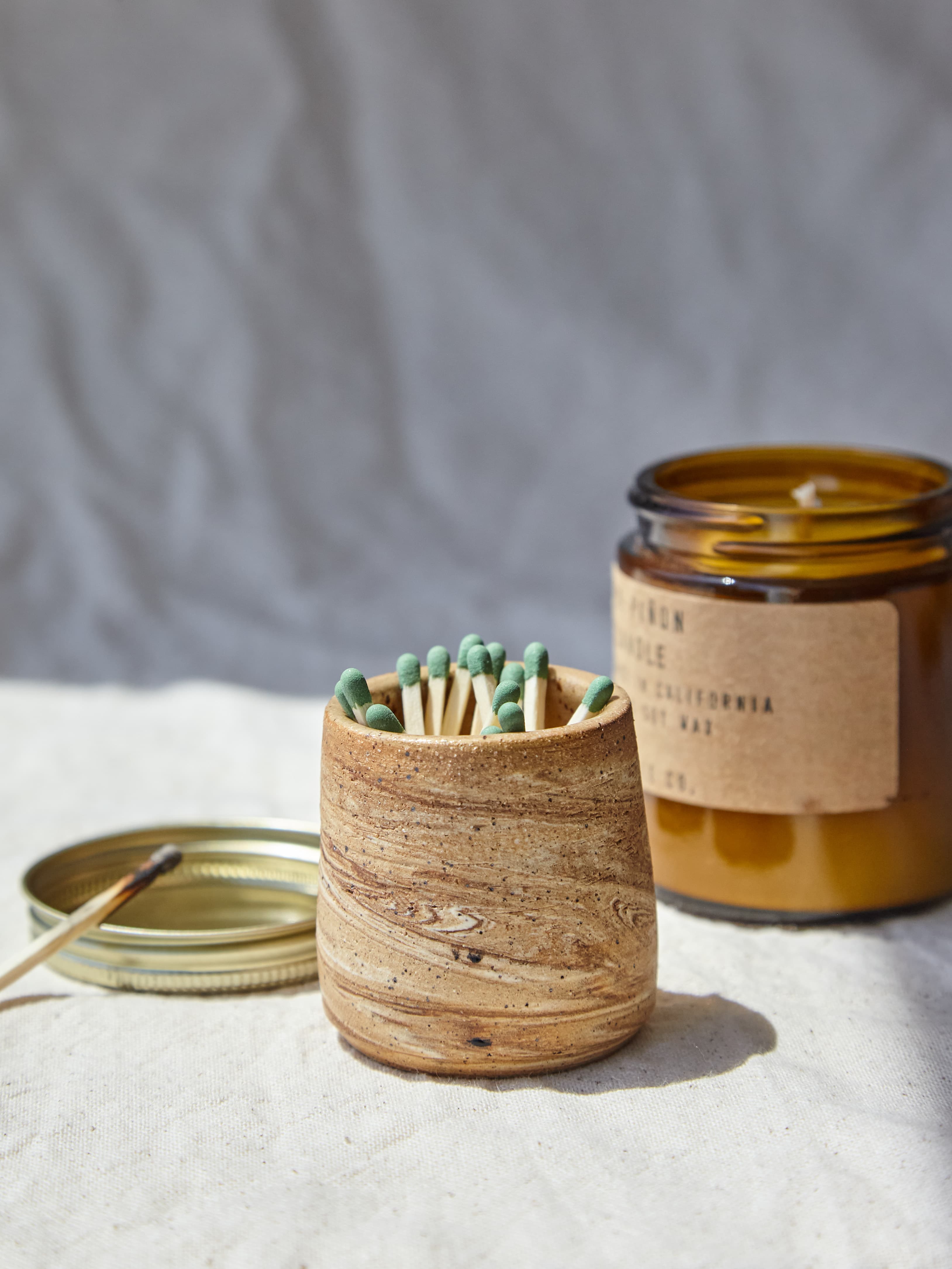 A handmade ceramic vessel styled with matches and a candle